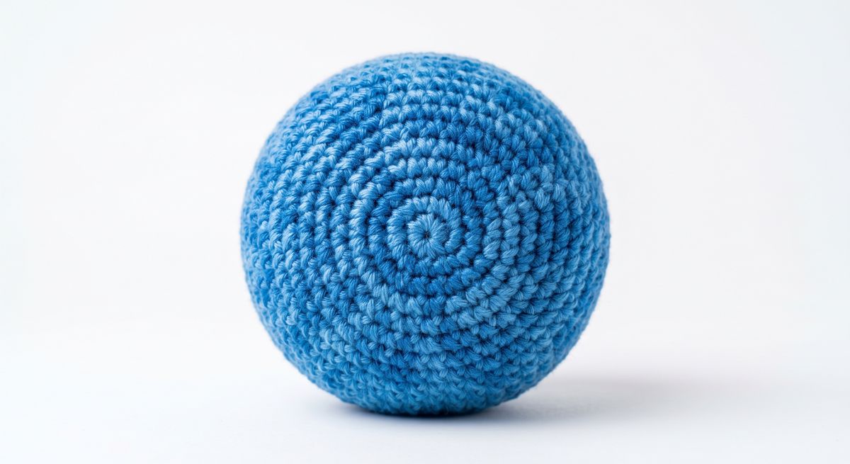 A plain blue crocheted sphere, the spiral of single crochet rounds clearly visible